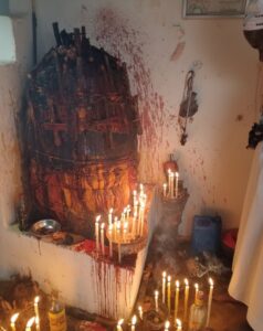 Partnerruckfuhrung Rituale Avec Voodoocompressed Stark Liebeszauber Ritual altar in a small room with many lit candles around a blood-stained wall and a large wrapped bundle in the corner